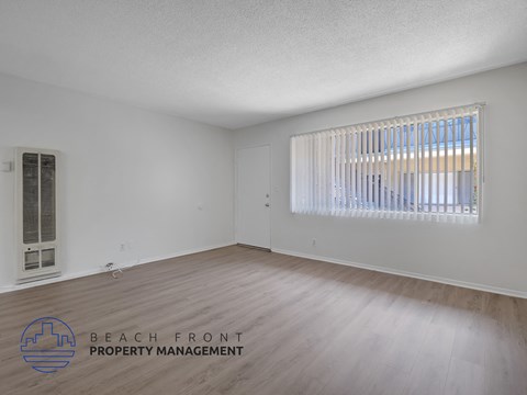 A room with wooden flooring and a window with blinds.
