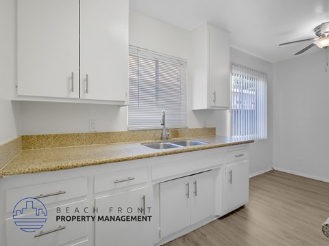 A kitchen with white cabinets and a granite countertop.