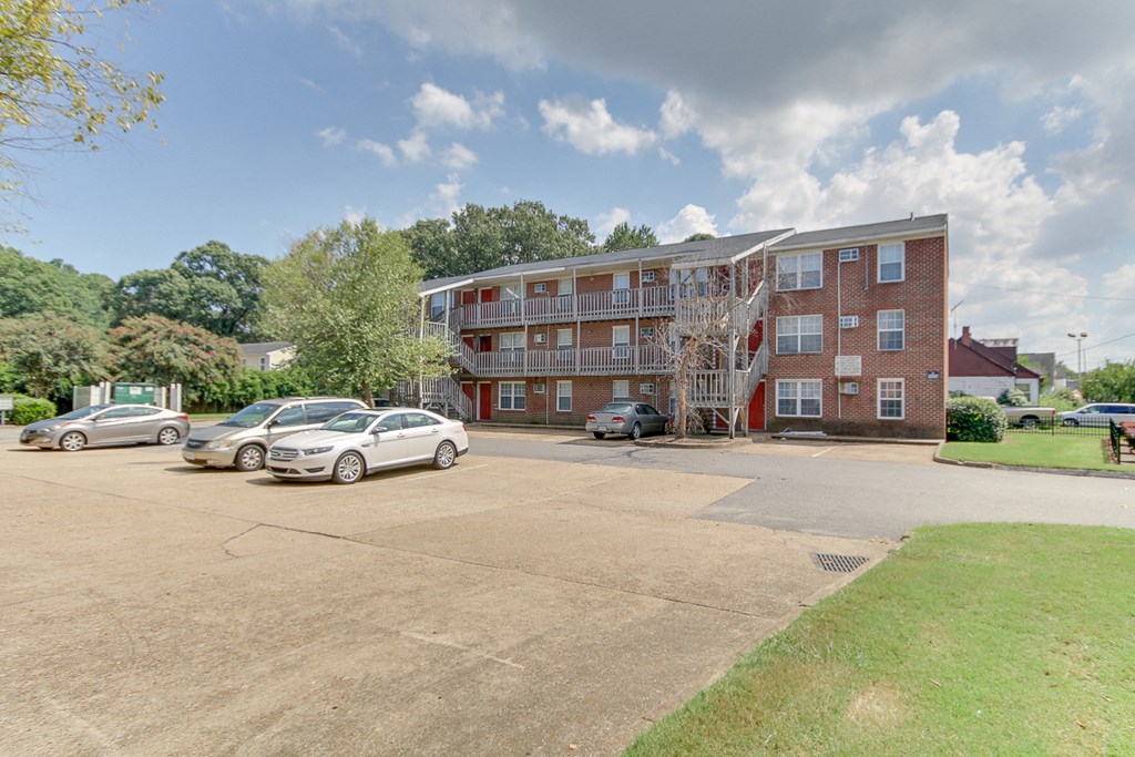 a large brick apartment building with cars parked in a parking lot