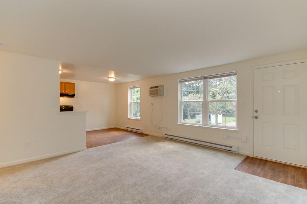 an empty living room with a large window and a kitchen