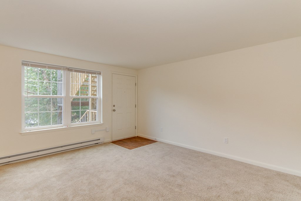 an empty living room with white walls and a window