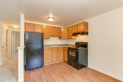 an empty kitchen with black appliances and wooden cabinets