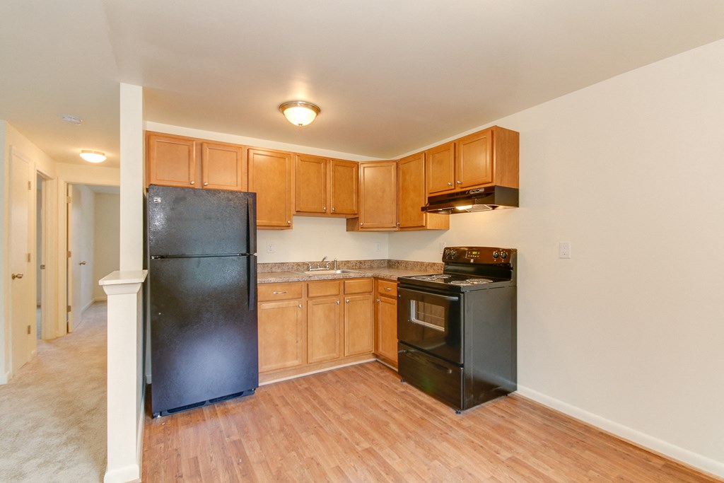 an empty kitchen with black appliances and wooden cabinets