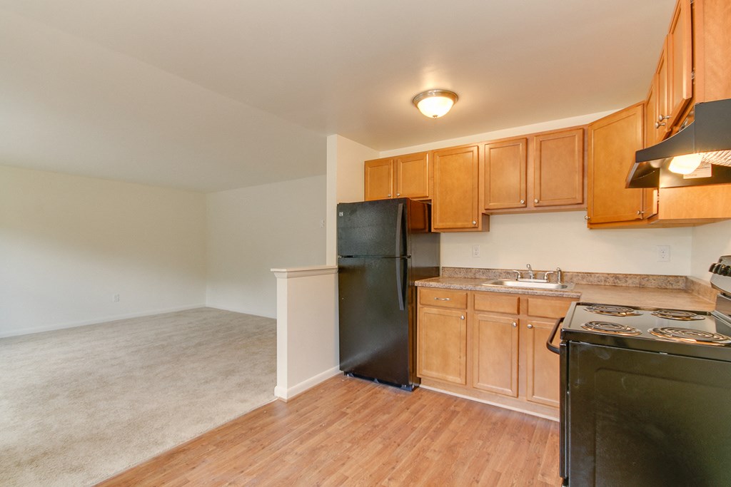an empty kitchen with black appliances and wooden cabinets