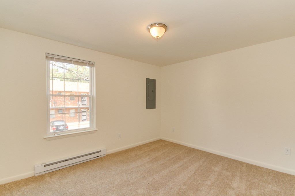 the spacious living room of an empty home with a large window