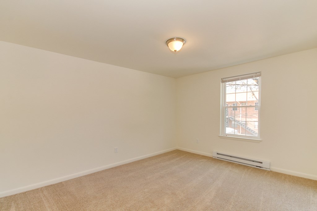 the living room of an empty home with carpet and a window