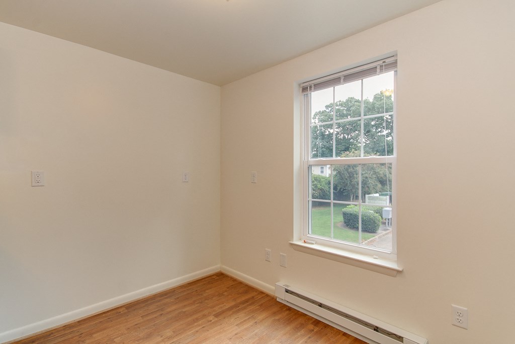 a bedroom with a large window and wood flooring