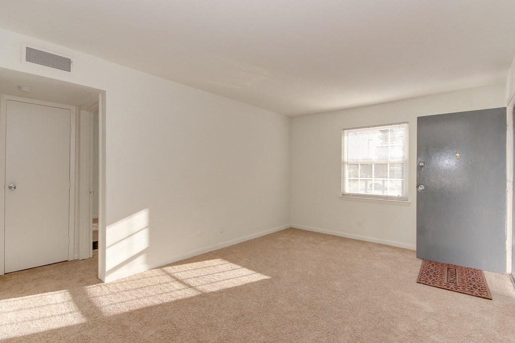 an empty living room with a door to a closet