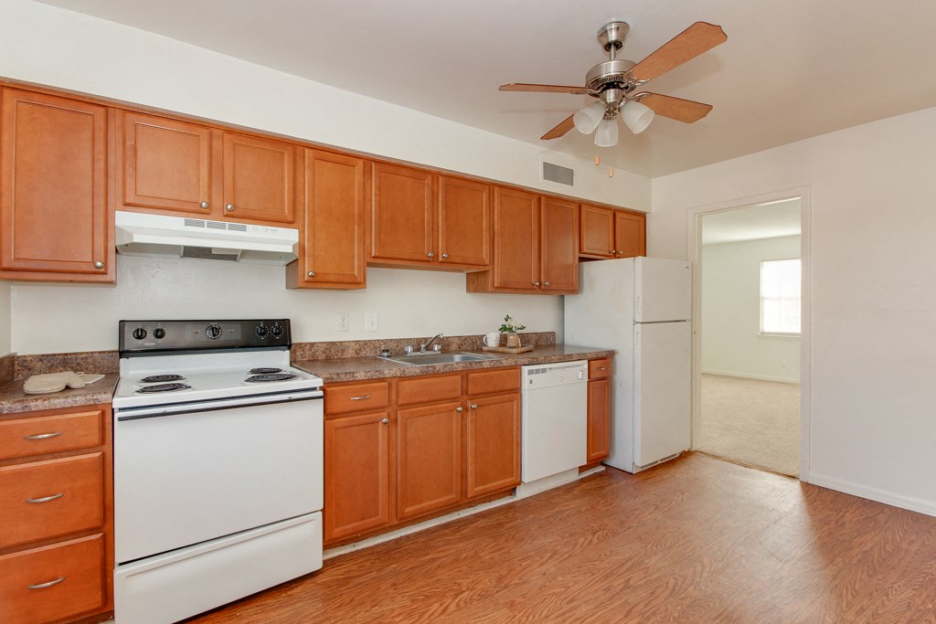a kitchen with white appliances and wooden cabinets and a ceiling fan