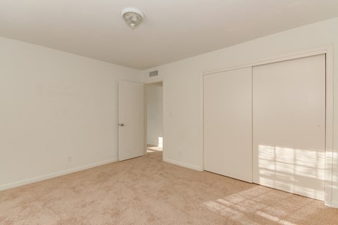 a bedroom with white walls and white closets and carpet
