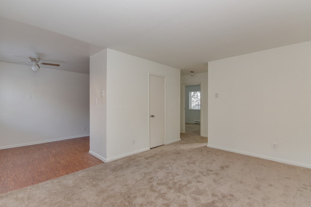 an empty living room with white walls and a wooden floor