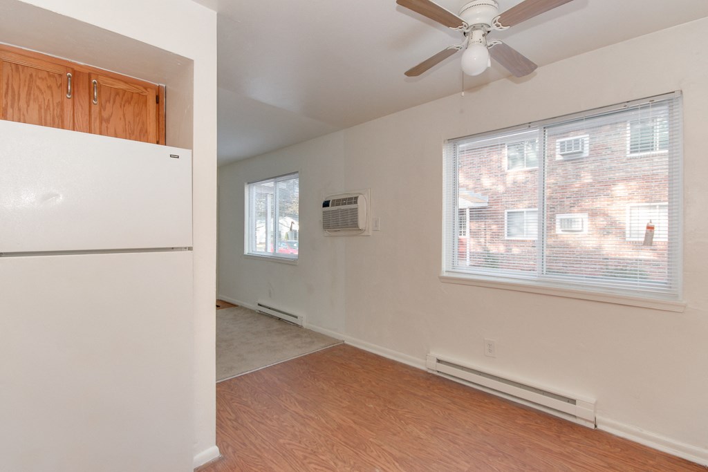 an empty living room with a refrigerator and a ceiling fan