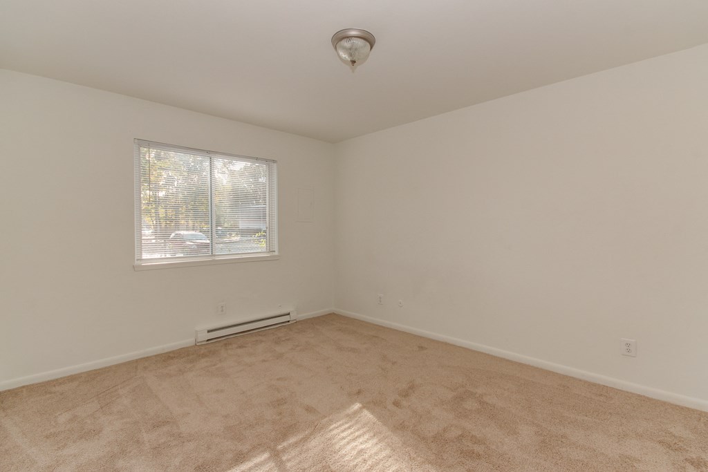 the living room of an empty home with a window and carpeting