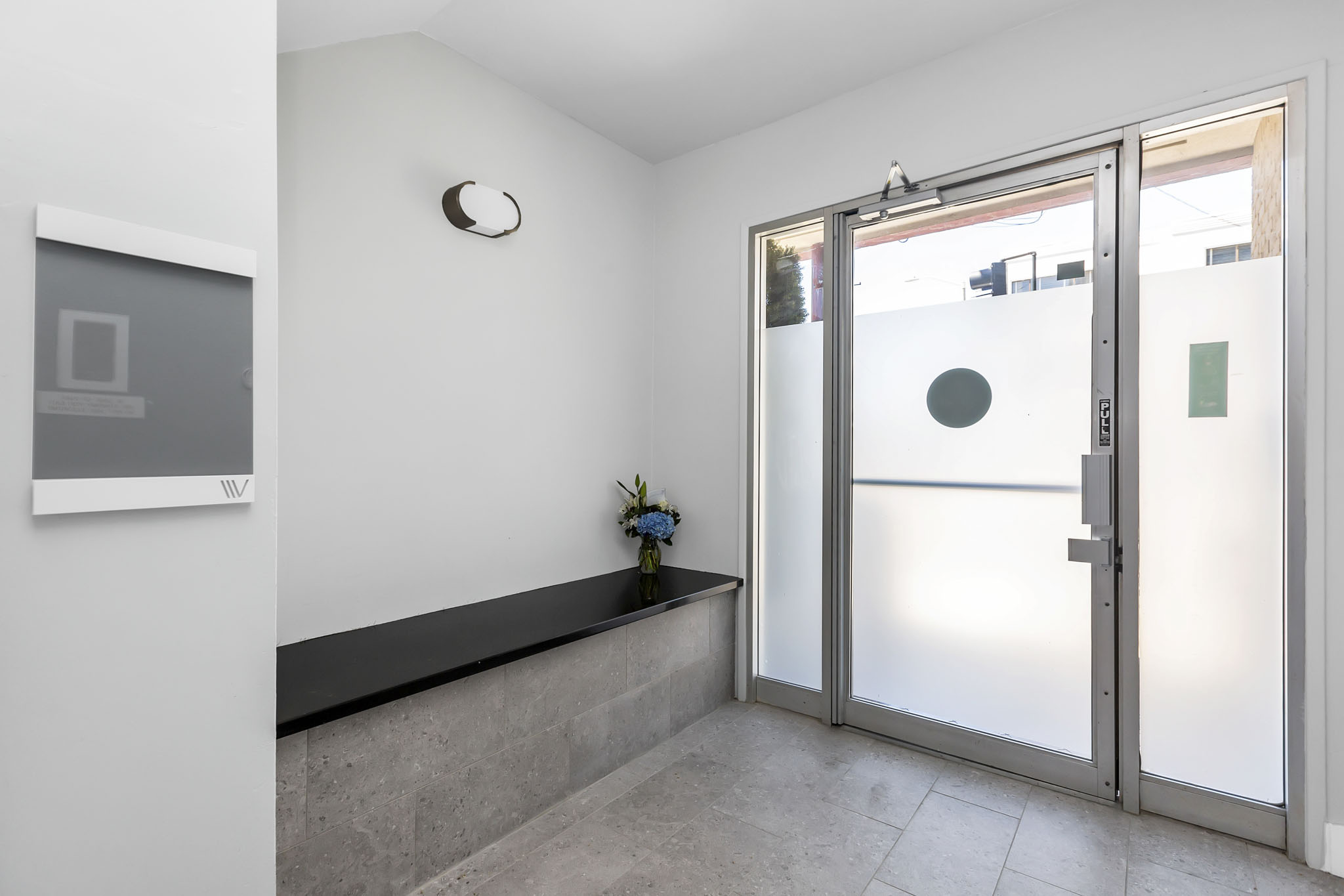 A glass door with a handle and a small plant on the ledge.