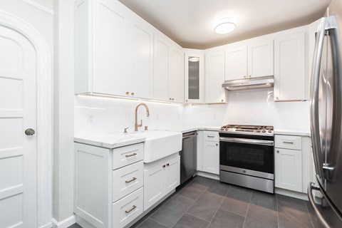 A kitchen with white cabinets and a stainless steel refrigerator.