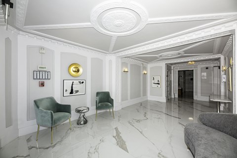 A white hallway with a green chair and a grey couch.