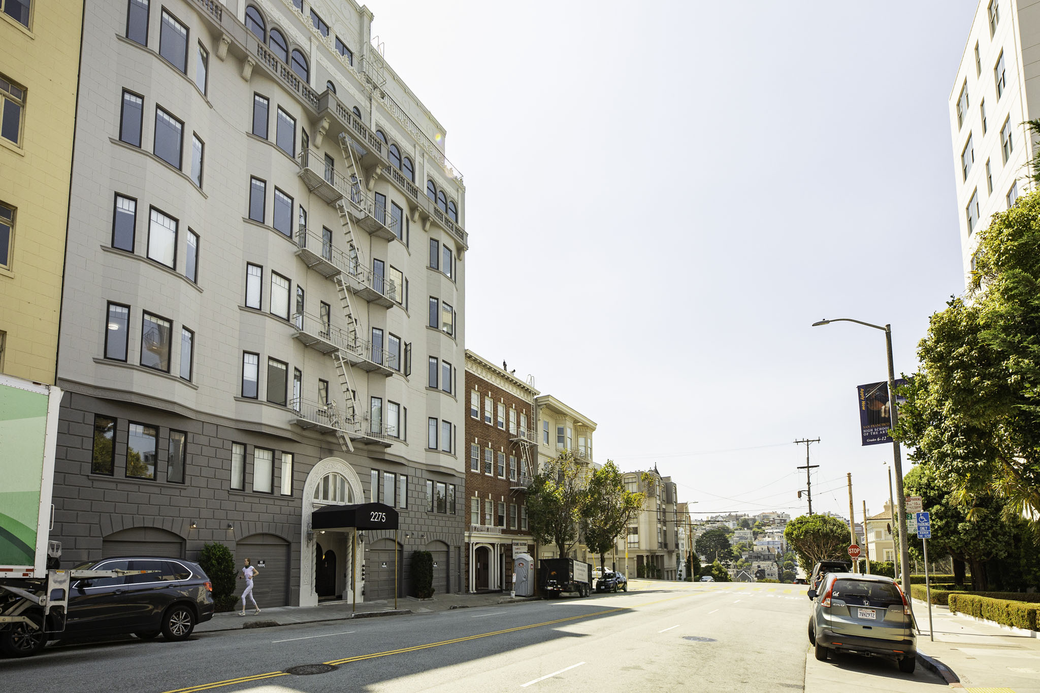 A street view of a residential area with cars parked on the side of the road.