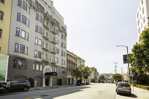 A street view of a residential area with cars parked on the side of the road.