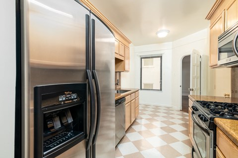 A modern kitchen with a checkered floor and a refrigerator on the left.