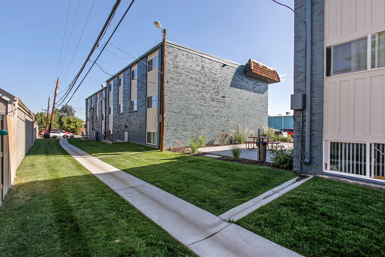 a sidewalk in front of a brick building with grass