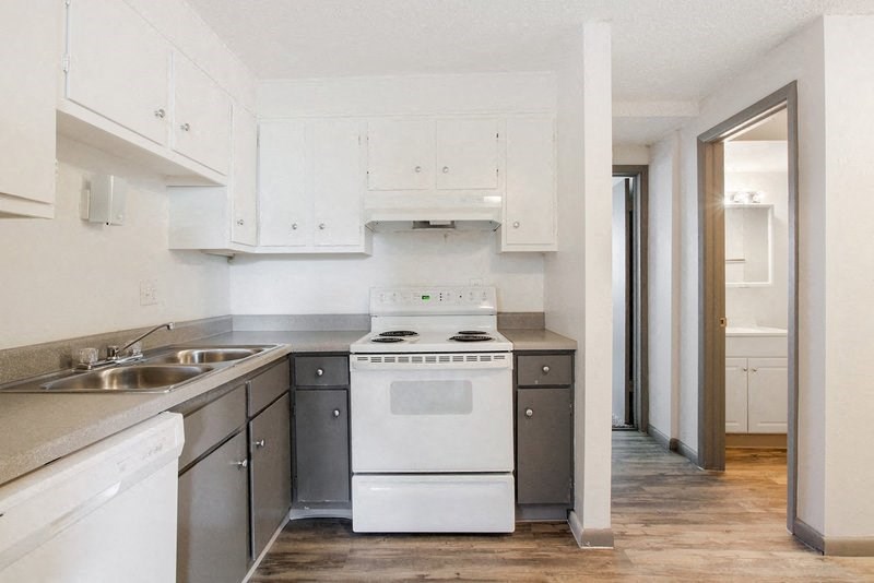 an empty kitchen with white appliances and white cabinets