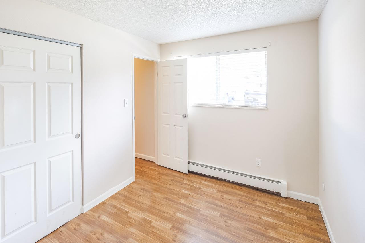 a bedroom with a door and a window and a wood floor