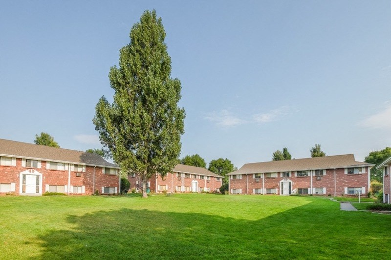 a group of brick apartment buildings on a green lawn