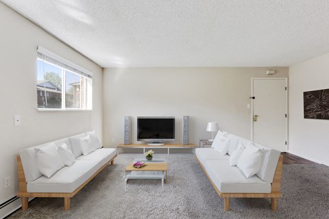 a living room with white couches and a television