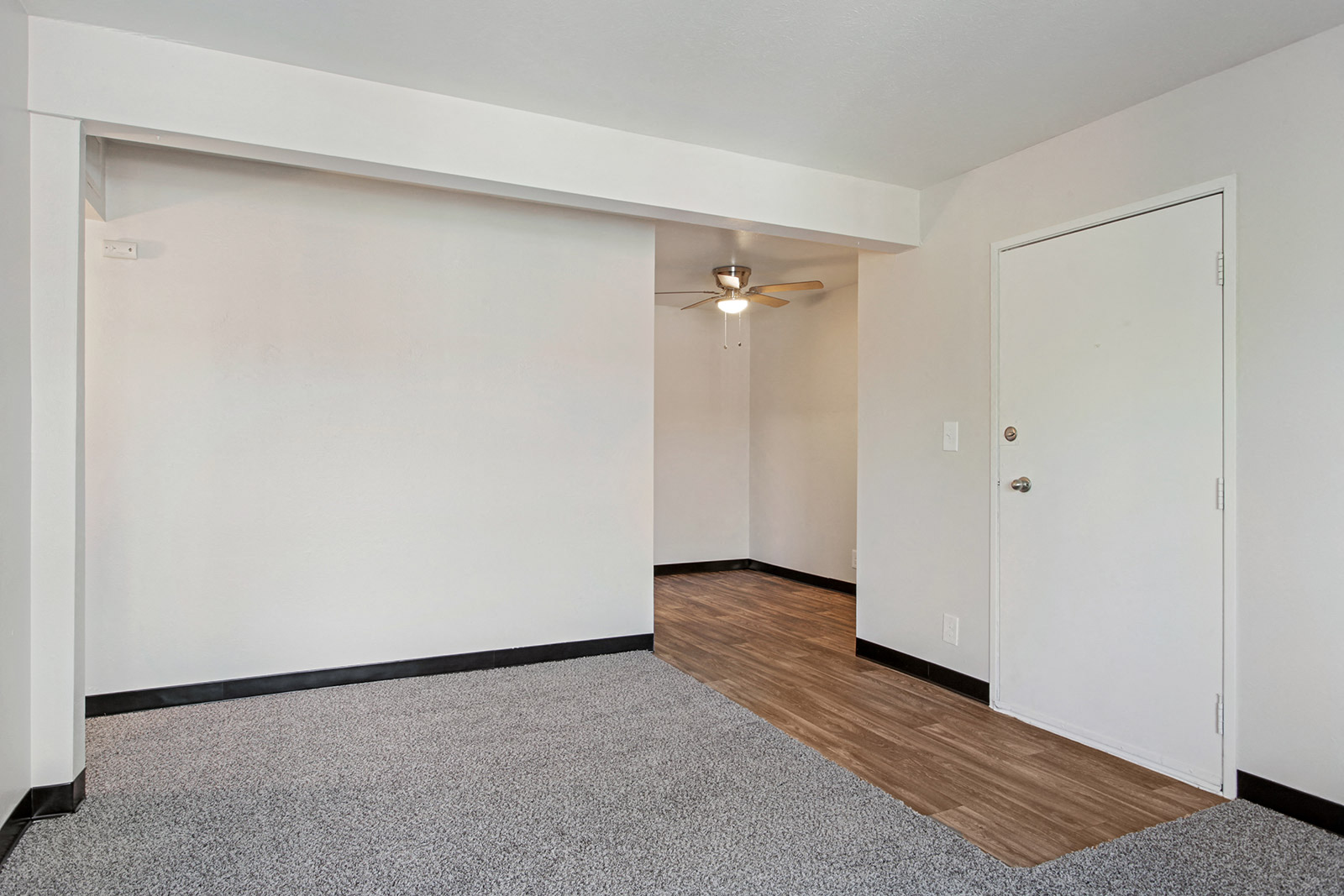 a bedroom with white walls and wood flooring and a ceiling fan
