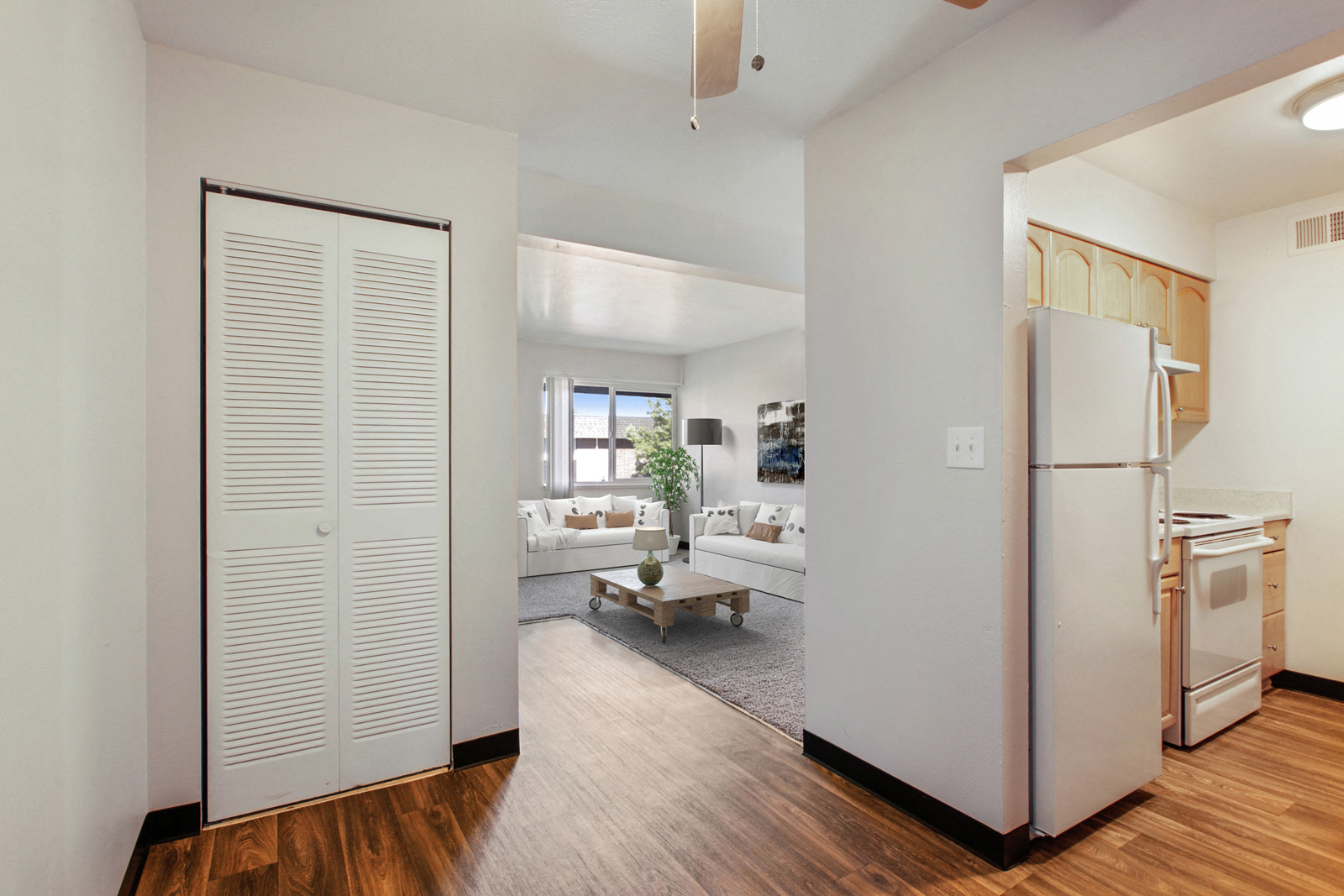 a kitchen and living room with a refrigerator and a door to the living room