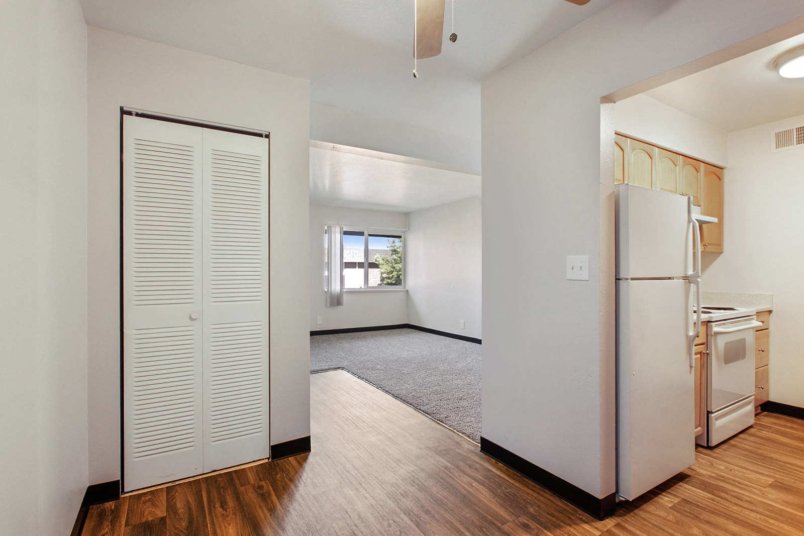 an empty kitchen and living room with a white refrigerator