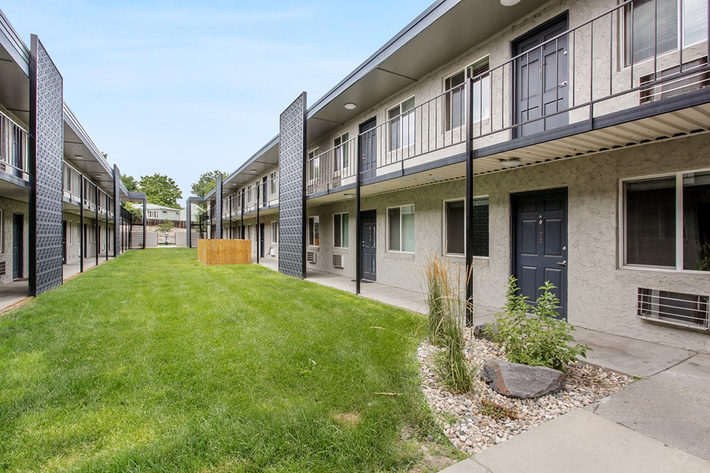 the courtyard of a building with a green lawn and a blue door