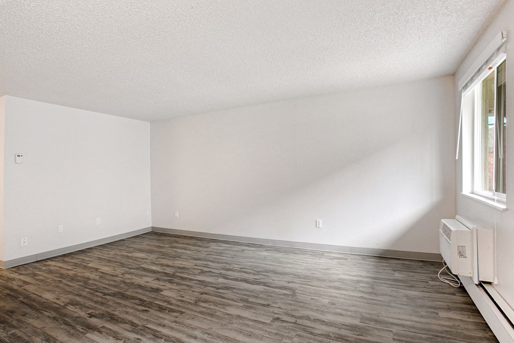 an empty living room with wood floors and white walls
