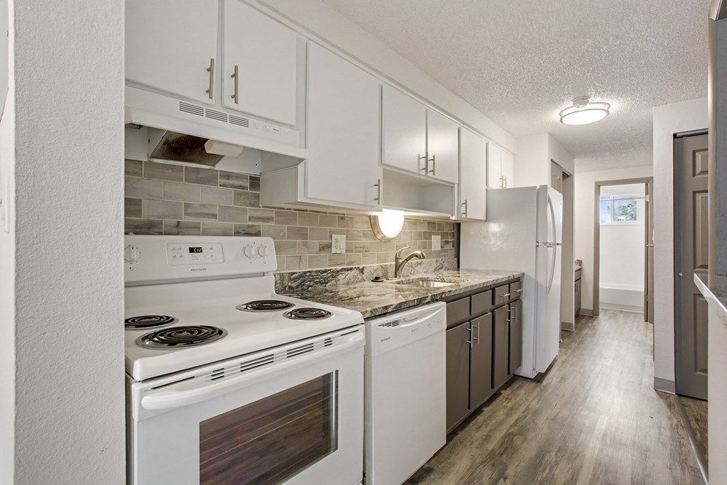 an empty kitchen with white appliances and white cabinets