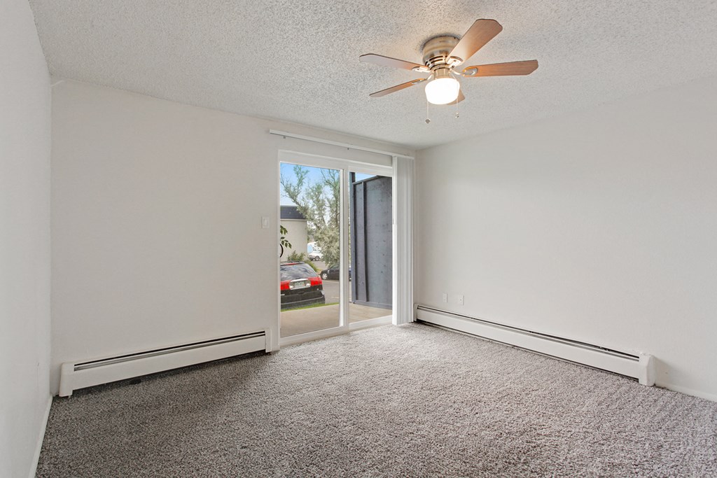 an empty living room with a ceiling fan and a window
