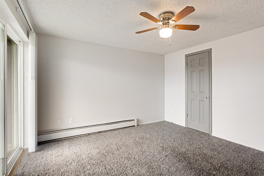 an empty room with a ceiling fan and a door