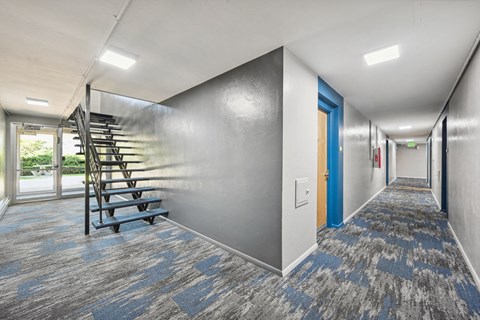 a long hallway with a spiral staircase on the wall and a blue door