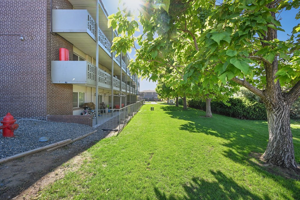 an apartment building with a green lawn and a red fire hydrant