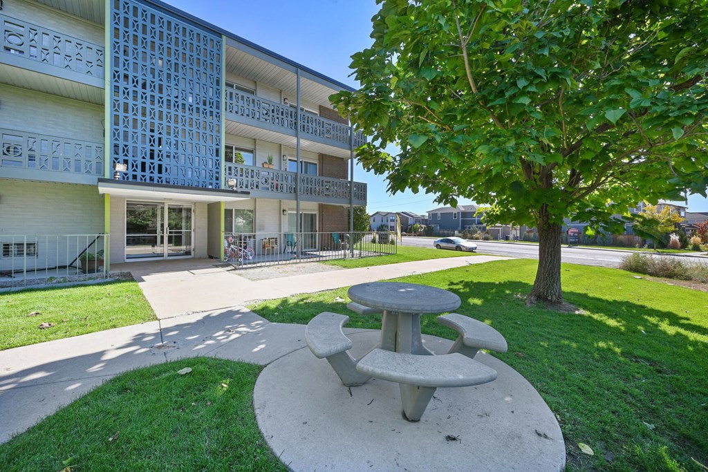 a picnic table in front of a building with a tree