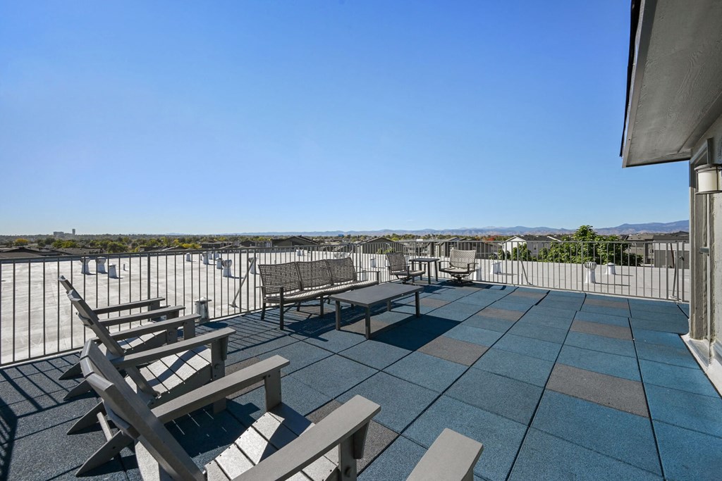 a rooftop patio with benches and tables and a view of the mountains