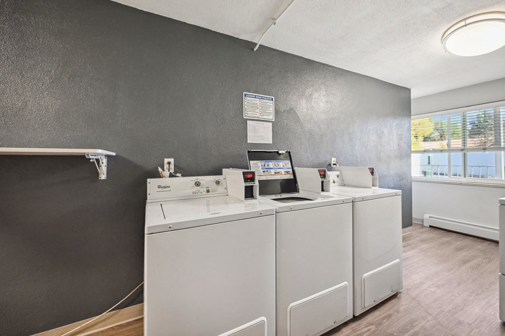 four washers and dryers in a room with a window and a laundry room