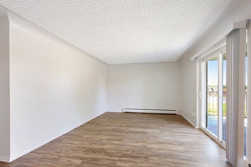 an empty living room with wood flooring and a sliding glass door