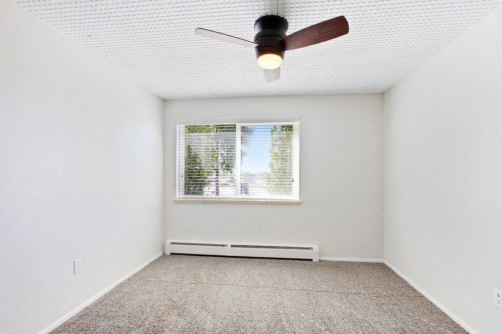 an empty room with a window and a ceiling fan