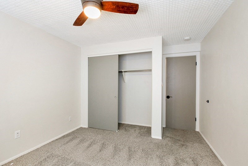 an empty bedroom with a closet and a ceiling fan