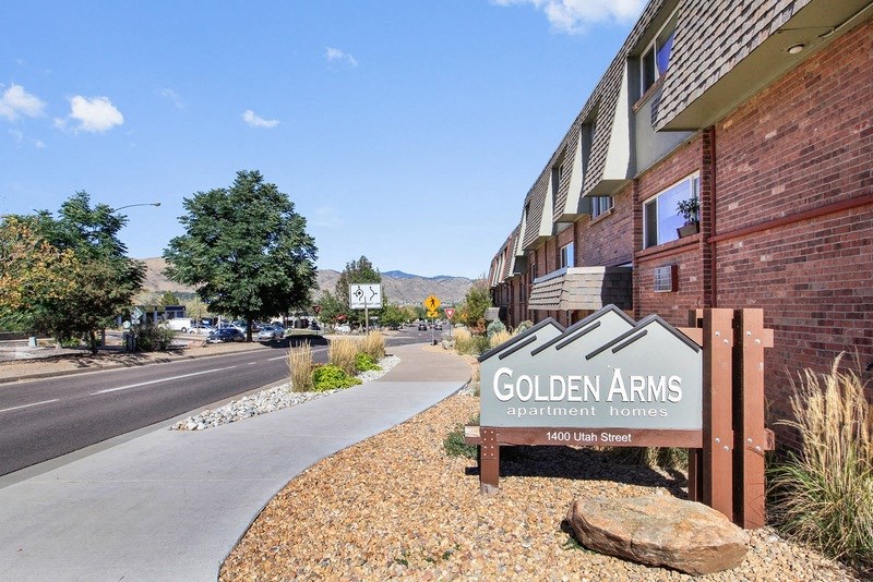 a sign for the golden arms apartment complex on the side of a street