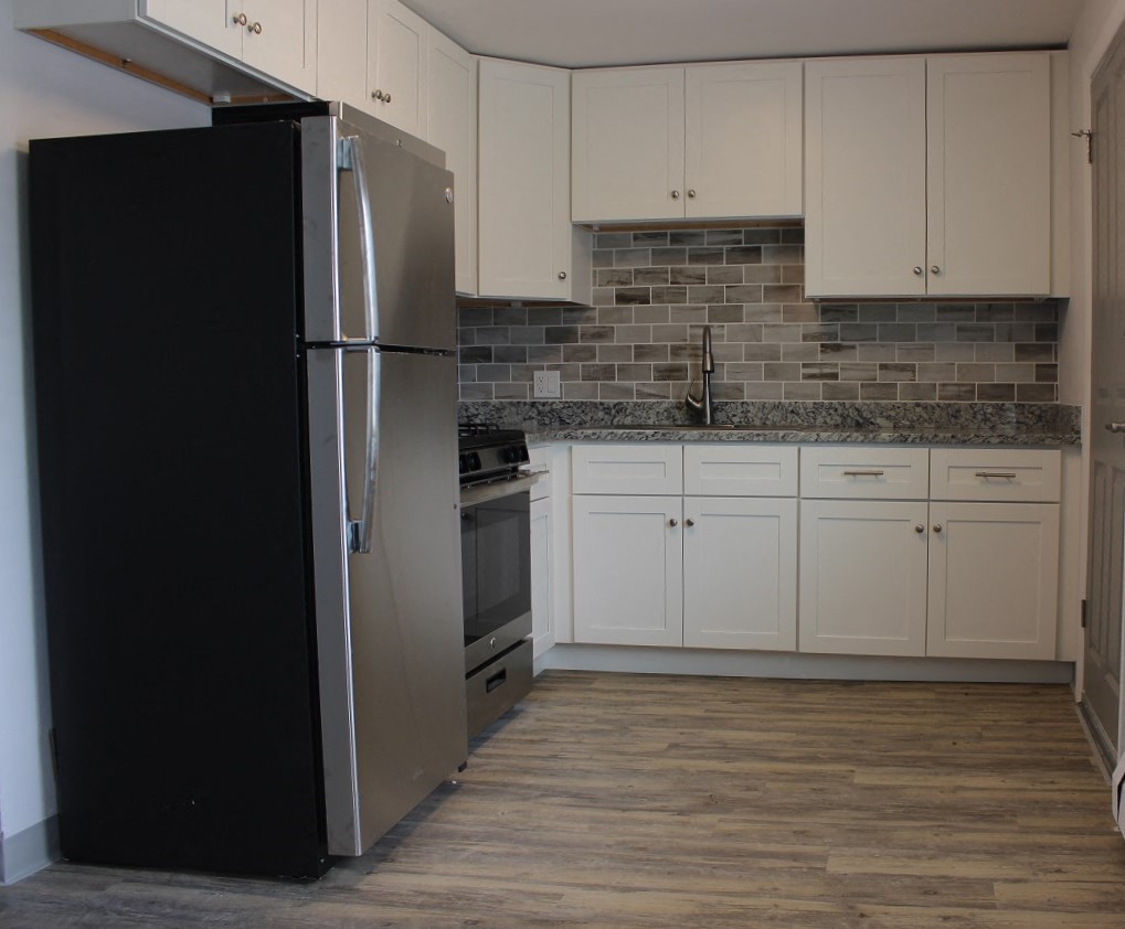 a kitchen with white cabinets and a stainless steel refrigerator