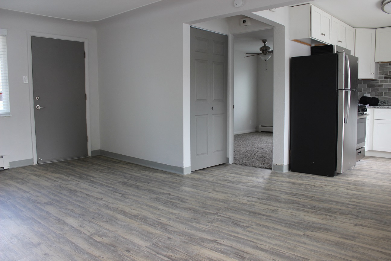 an empty kitchen with a refrigerator and a door to a hallway