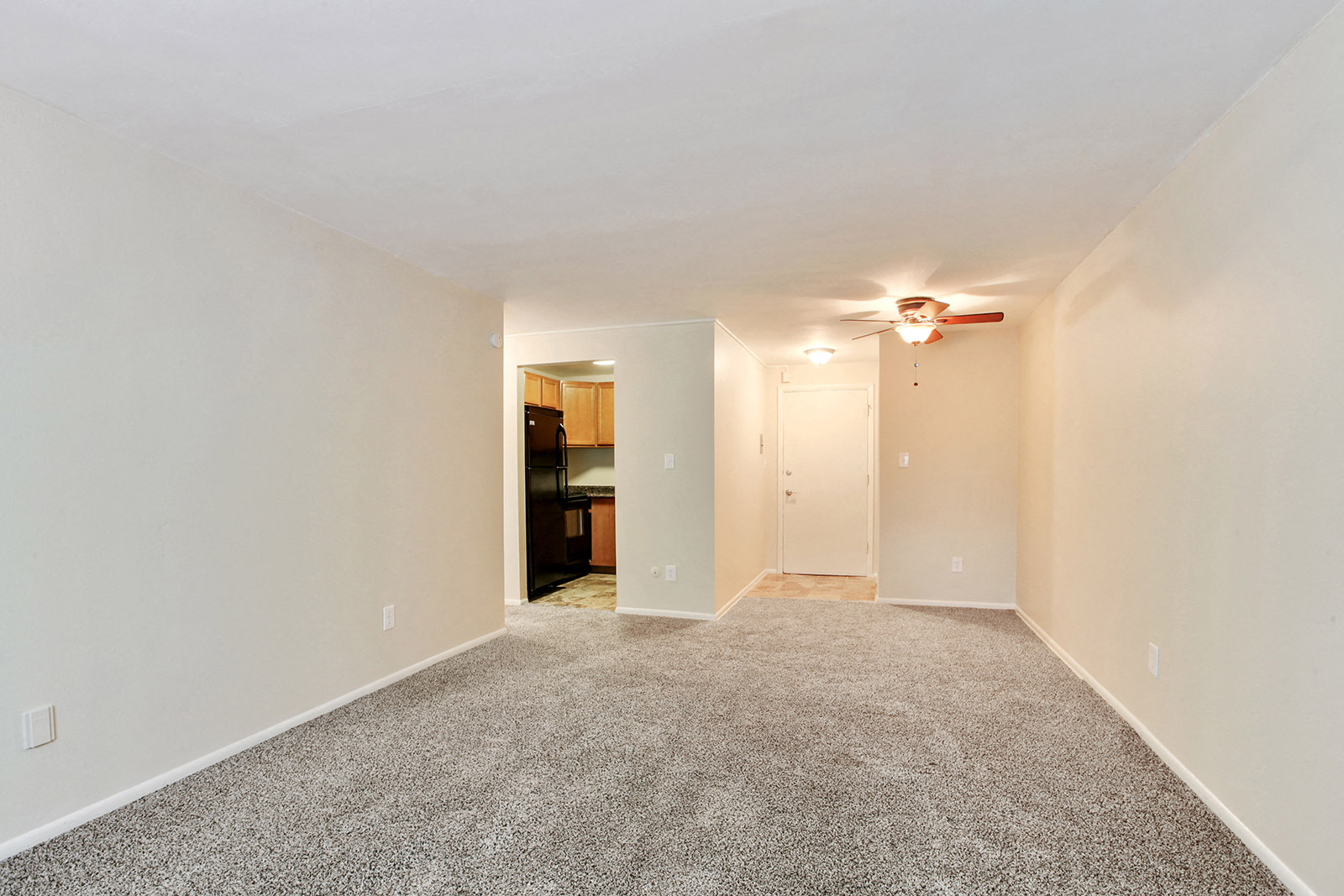 a spacious living room with carpet and a ceiling fan