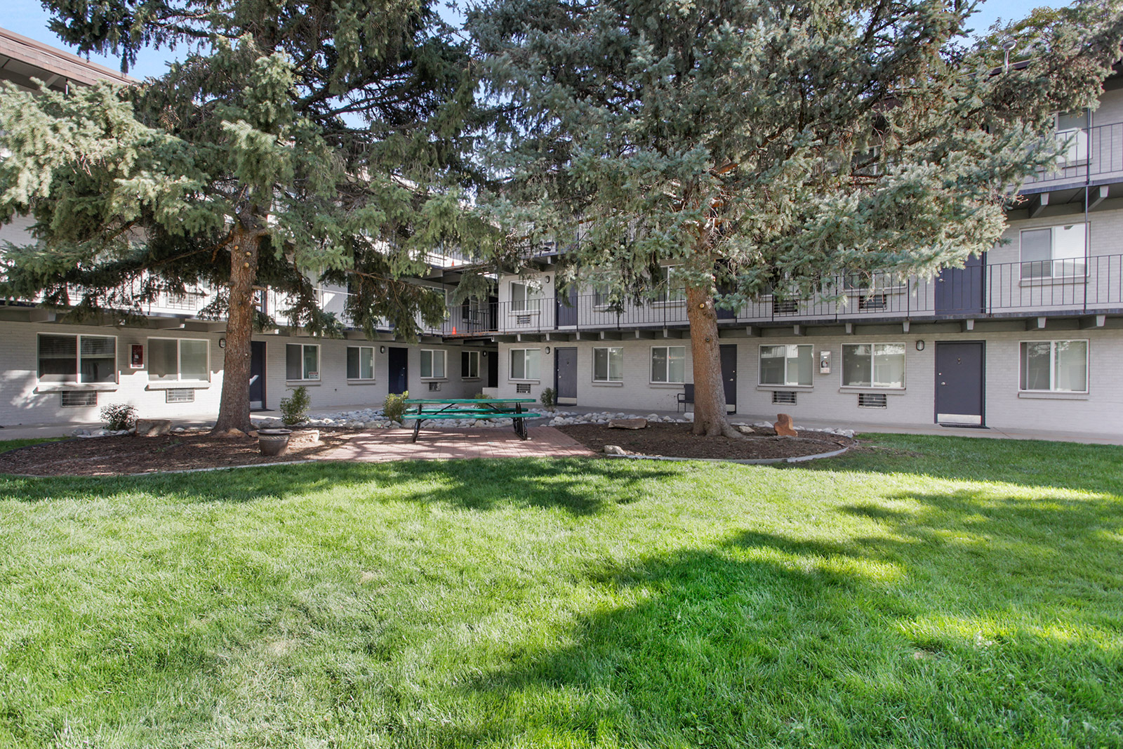 a park with trees and a bench in front of an apartment building