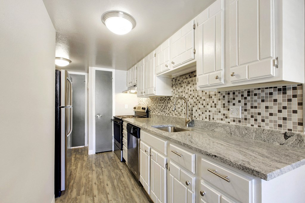 a renovated kitchen with white cabinets and granite counter tops